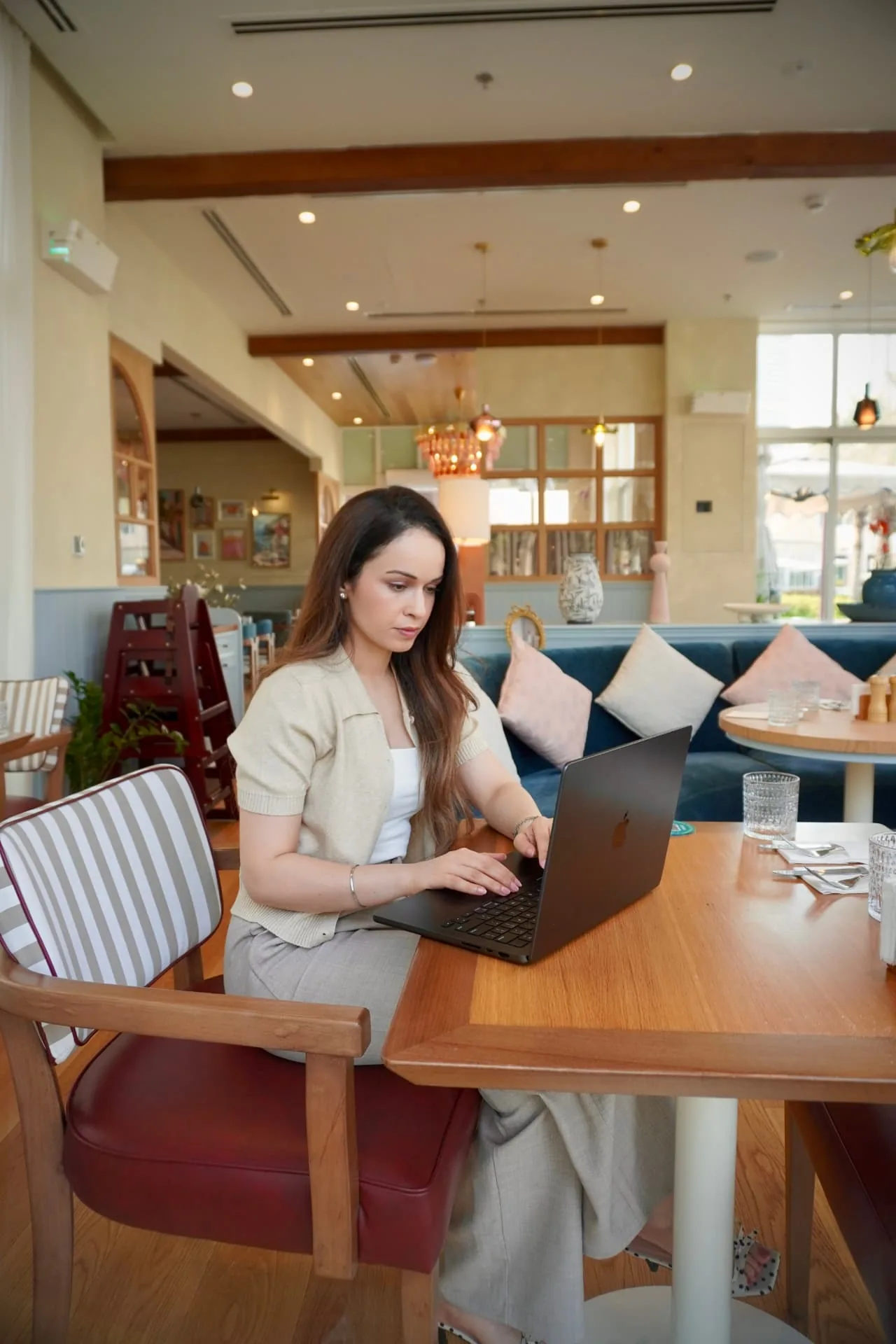 Komel Kaur working on a laptop at a cafe table